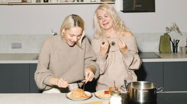 A mother and daughter in the kitchen together cooking a healthy pasta meal